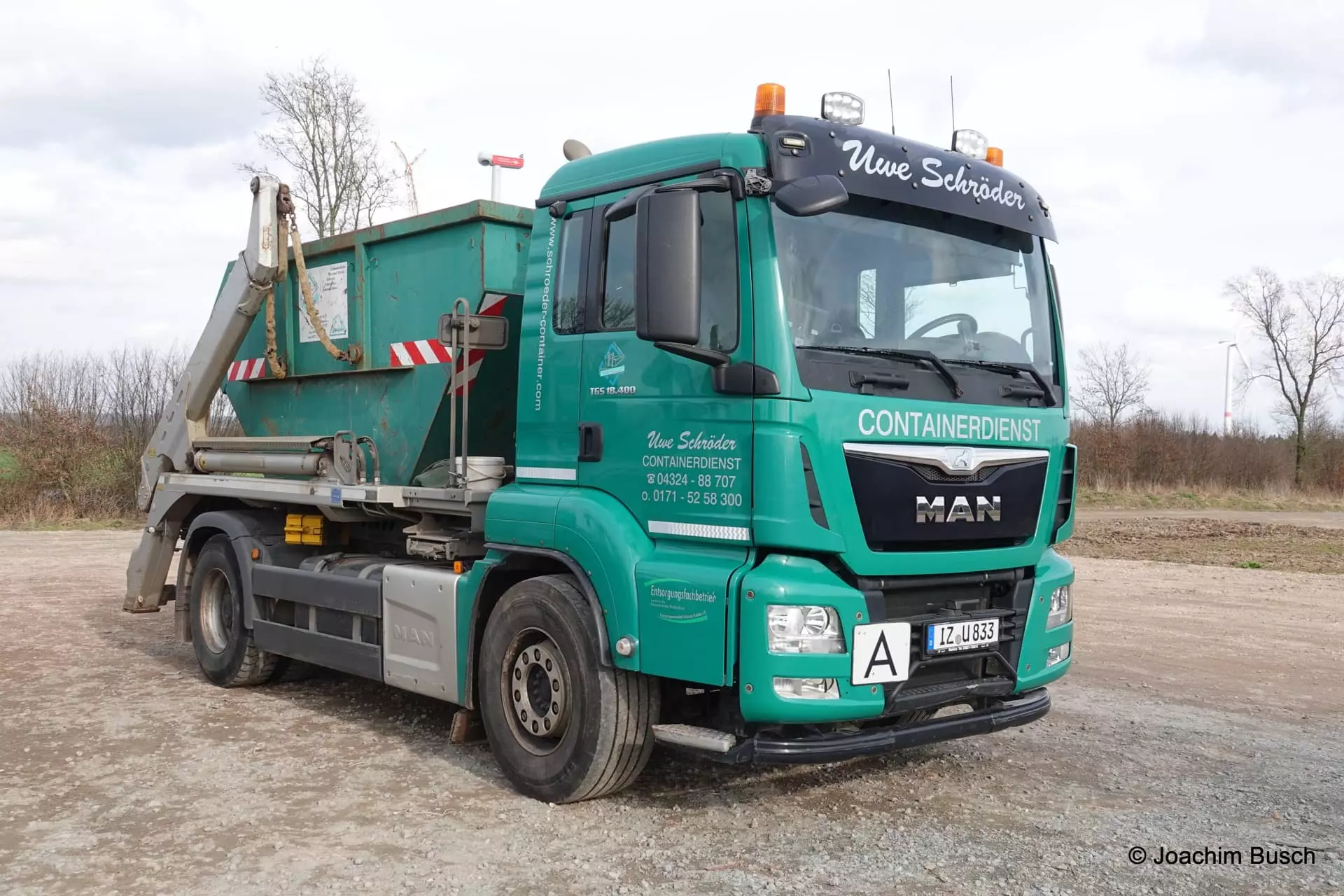 Türkiser MAN Absetzkipper des Uwe Schröder Containerdienst mit Absetzmulde auf einem Platz