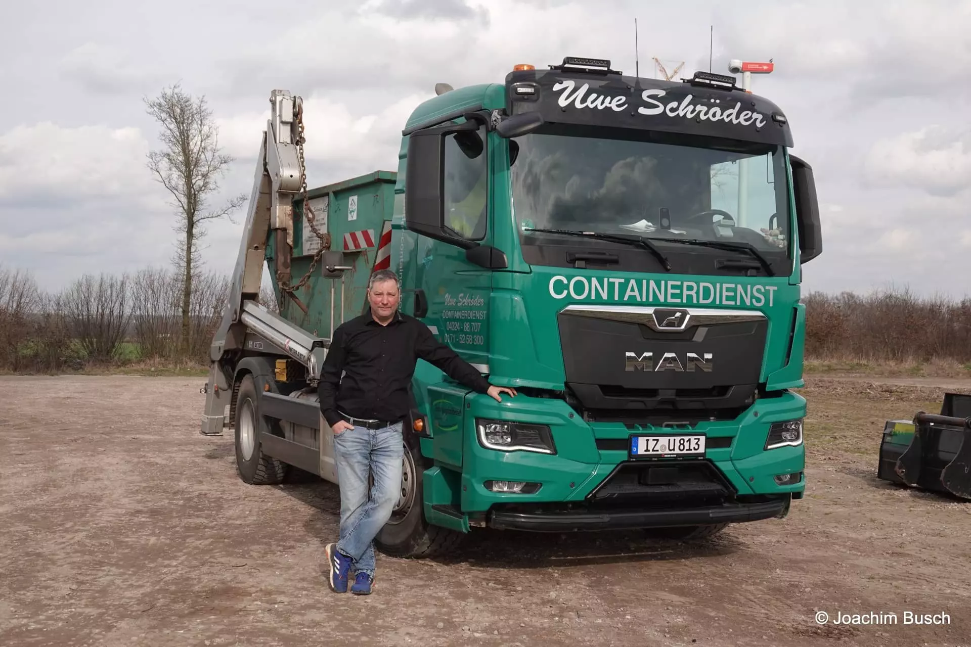 Mitarbeiter Thomas Leuschke vor einem MAN Absetzkipper des Uwe Schröder Containerdienst